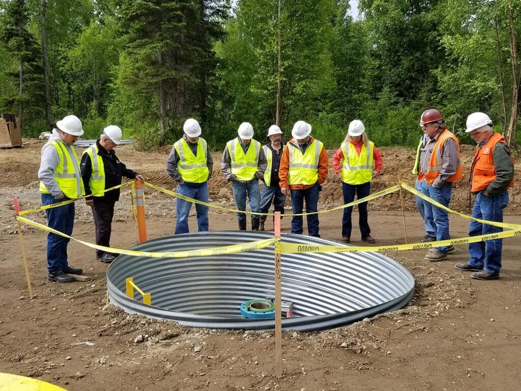 Workers around caution tape around an underground pipe